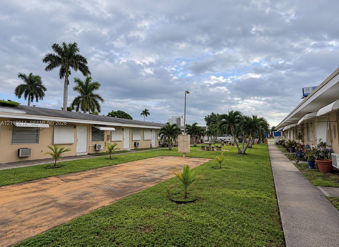Expansive landscaped grounds featuring mature palm trees, a concrete walkway, and centralized open green space
