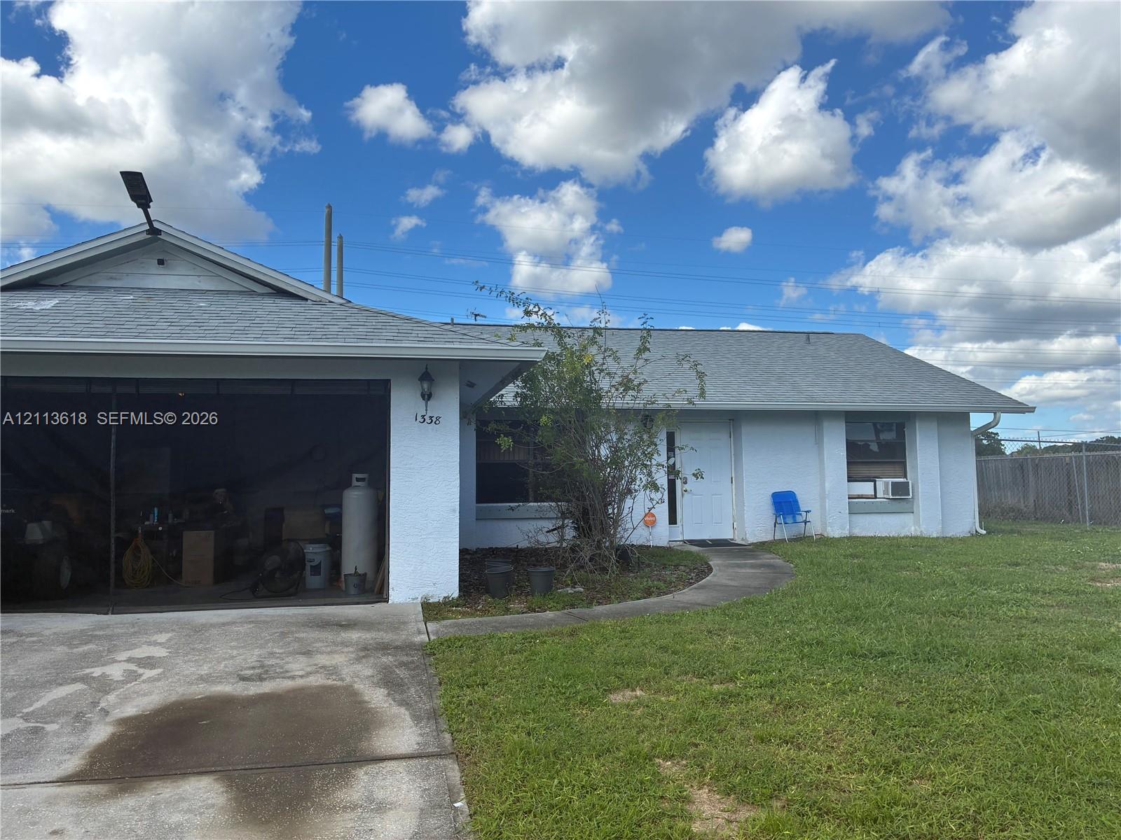 Stucco exterior featuring a concrete driveway, attached garage, and asphalt shingle roof