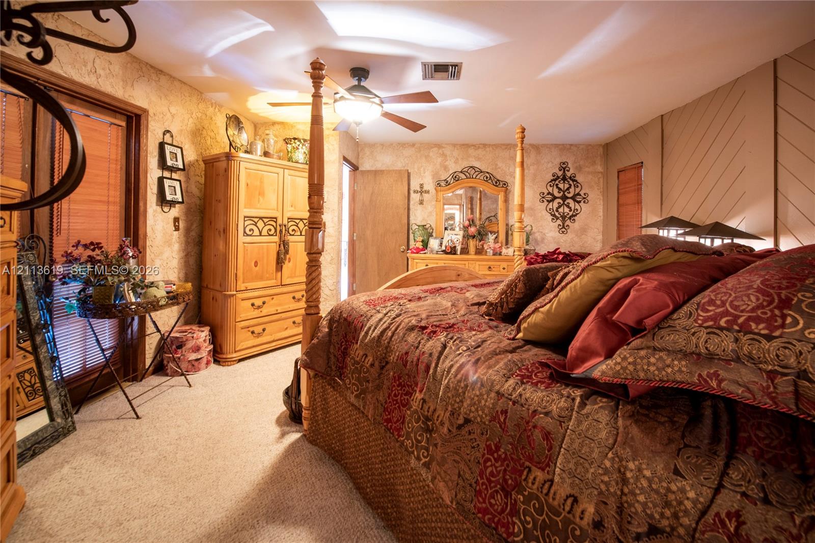 Carpeted interior featuring a ceiling fan with integrated lighting, wood-finish interior doors, and textured wall finish