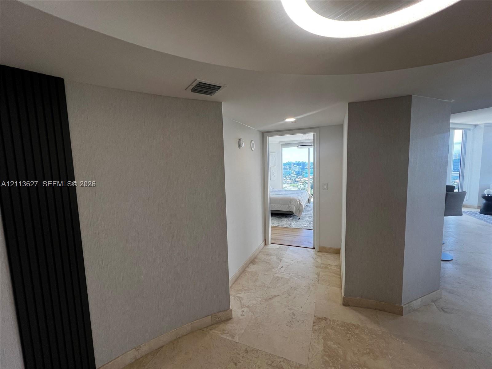 Curved ceiling architecture featuring a circular recessed lighting fixture, stone flooring, and vertical dark-toned decorative wall paneling