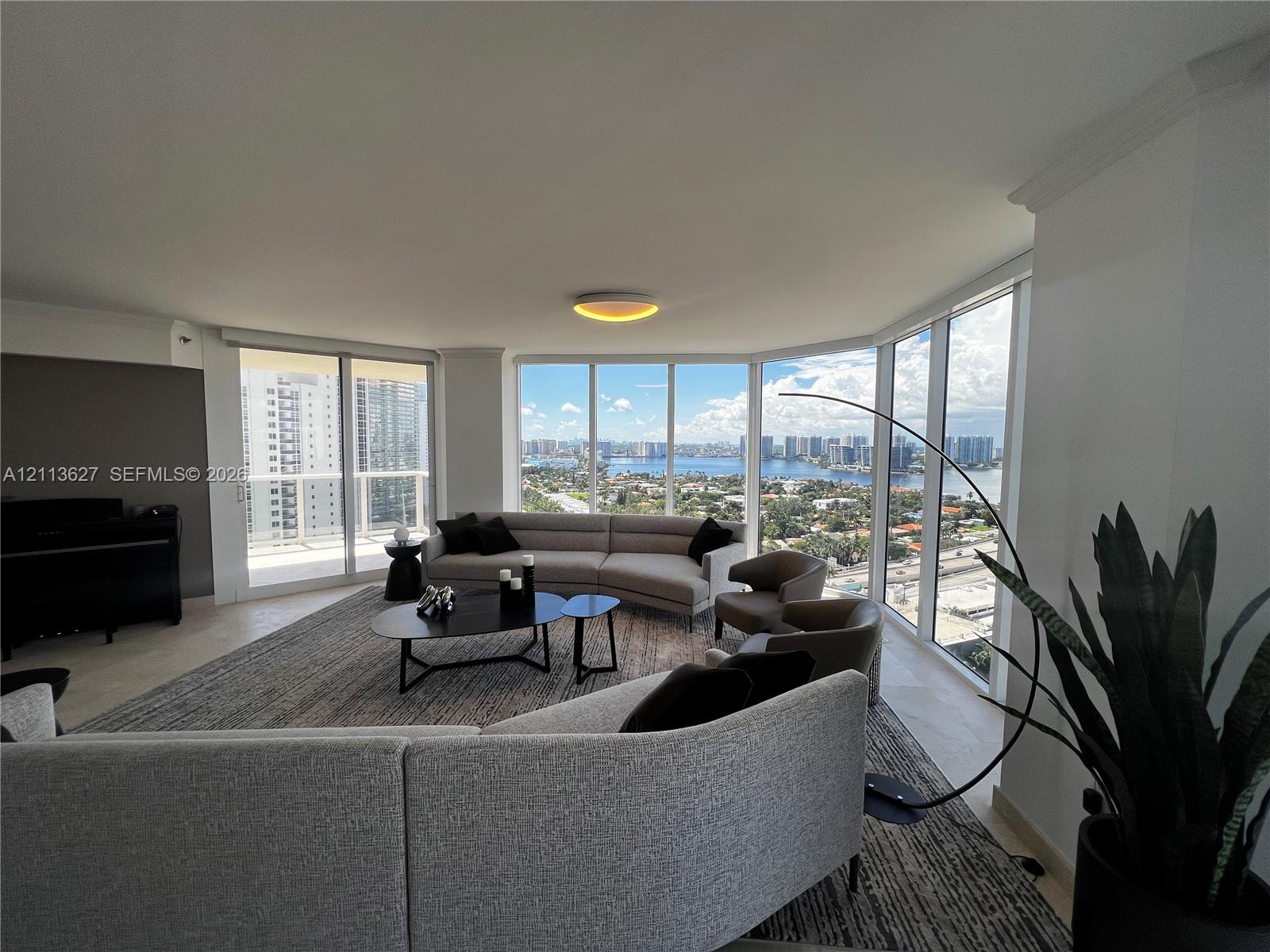 Floor-to-ceiling panoramic windows, sliding glass doors, neutral tile flooring, and crown molding