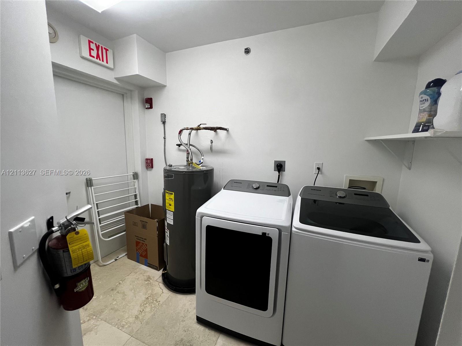 Utility room featuring stone-tile flooring and built-in shelving