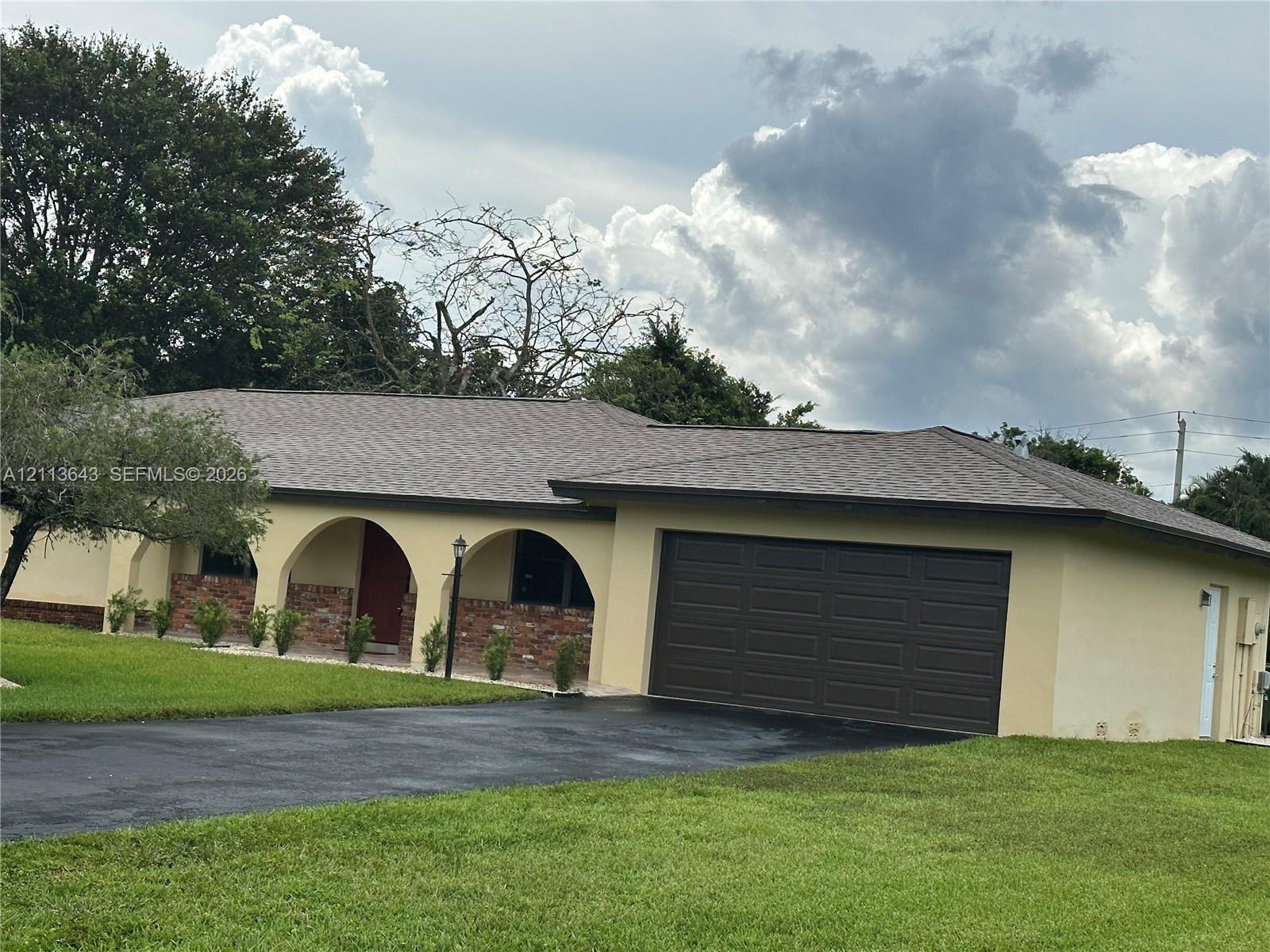 Single-story residence featuring a covered front porch with decorative masonry arches, brick veneer accents, an asphalt-shingle roof, and an attached two-car garage