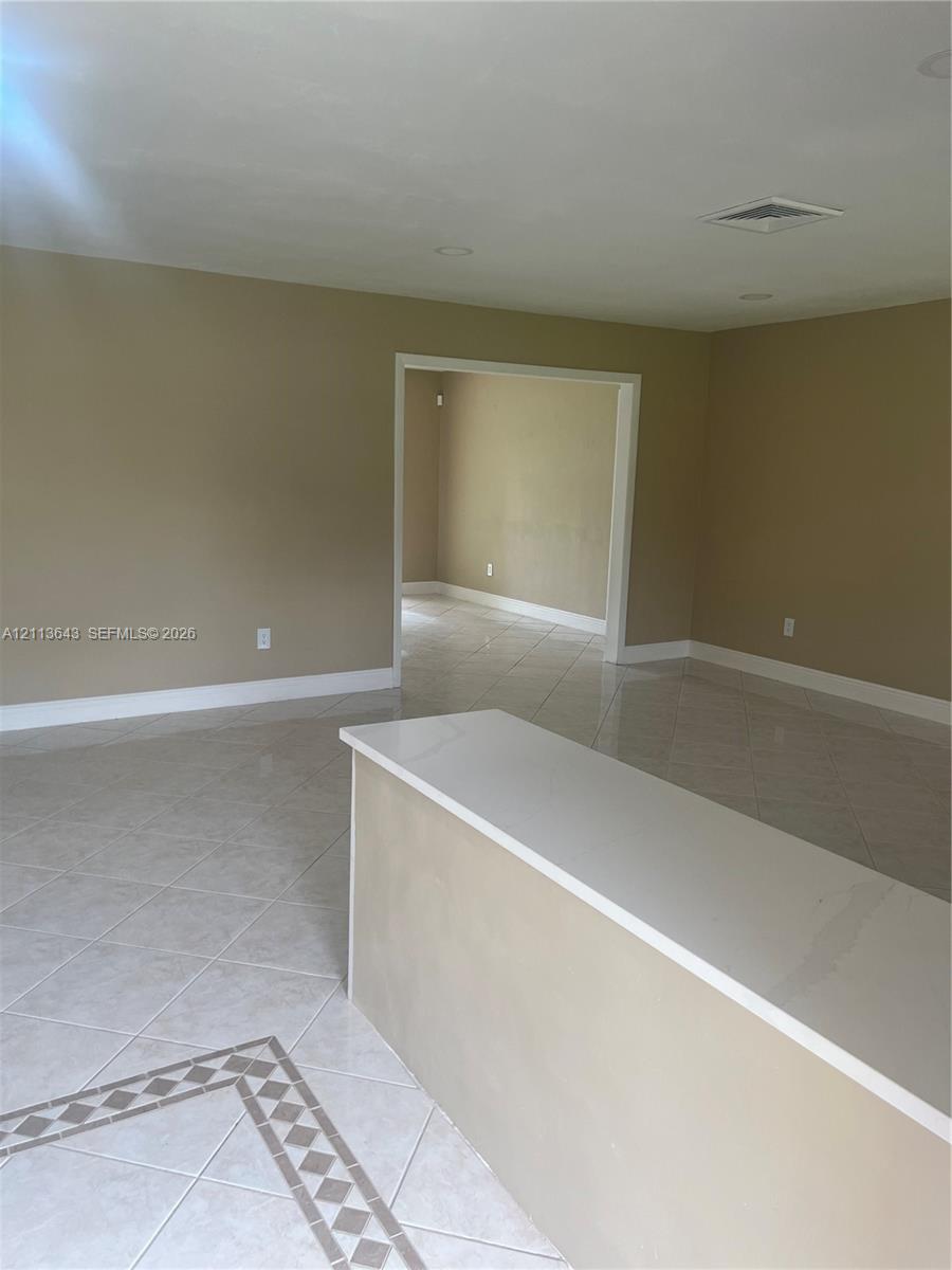 Neutral-toned interior featuring large-format diagonal tile flooring with decorative inlaid border and an integrated solid-surface countertop