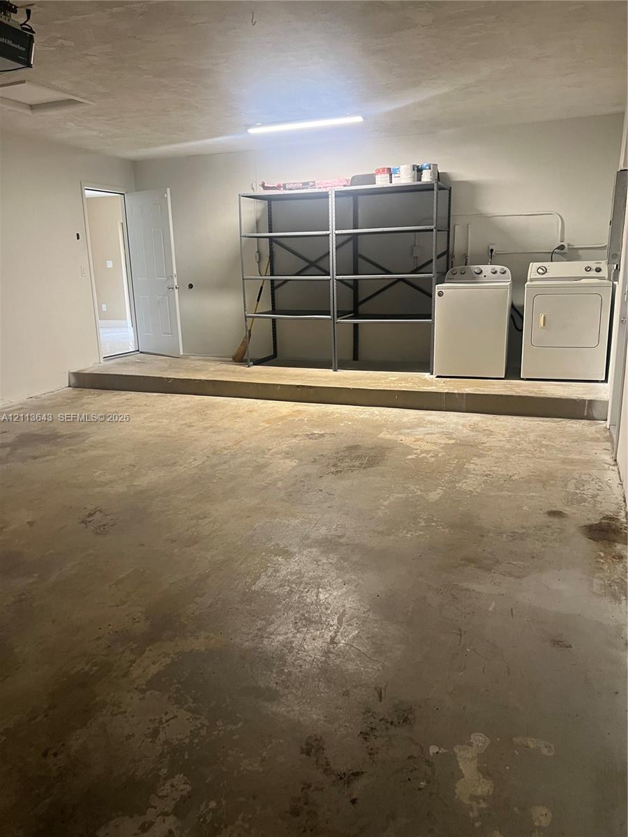 Multi-purpose utility space featuring a concrete floor, laundry hookups, linear overhead lighting, and an access door
