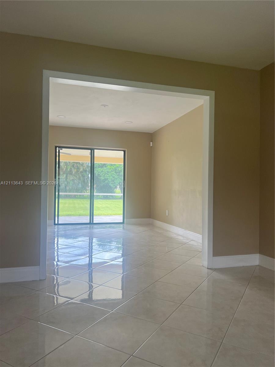 Large-format ceramic tile flooring, neutral wall tones, recessed ceiling lighting, and sliding glass doors featuring exterior visibility