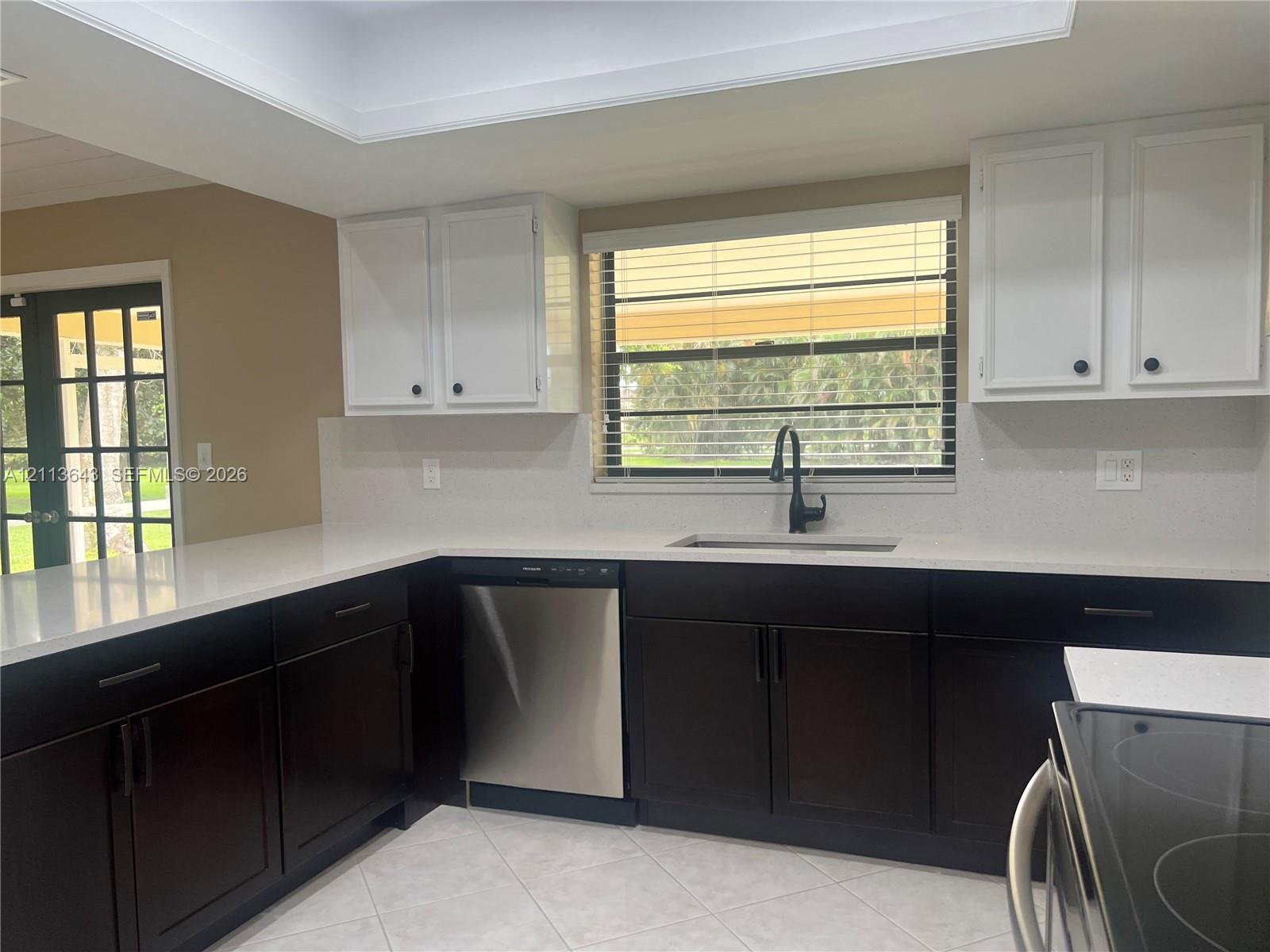 Kitchen featuringuu dual-tone cabinetry, stone-finish countertops, stainless steel dishwasher, undermount sink with a matte black faucet, and tile flooring