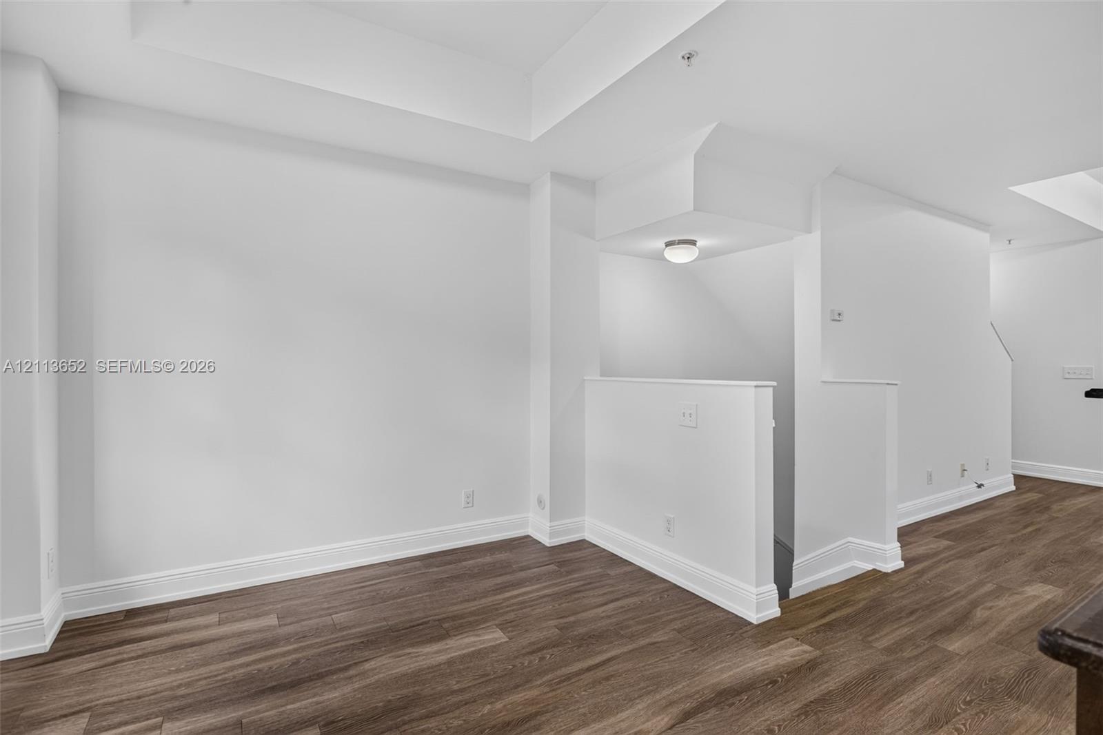 Interior space featuring wood-finish flooring, tray ceilings, and a flush-mount ceiling light