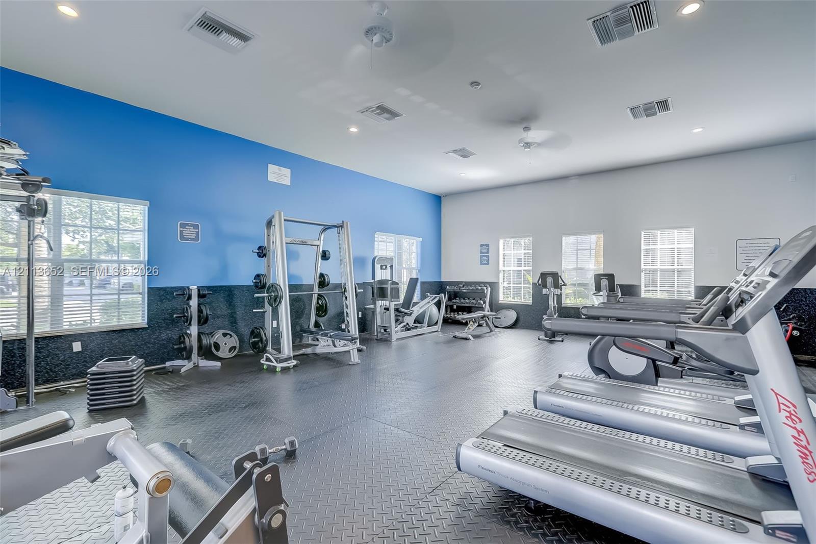 Fitness center featuring rubber flooring, recessed lighting, and multiple windows