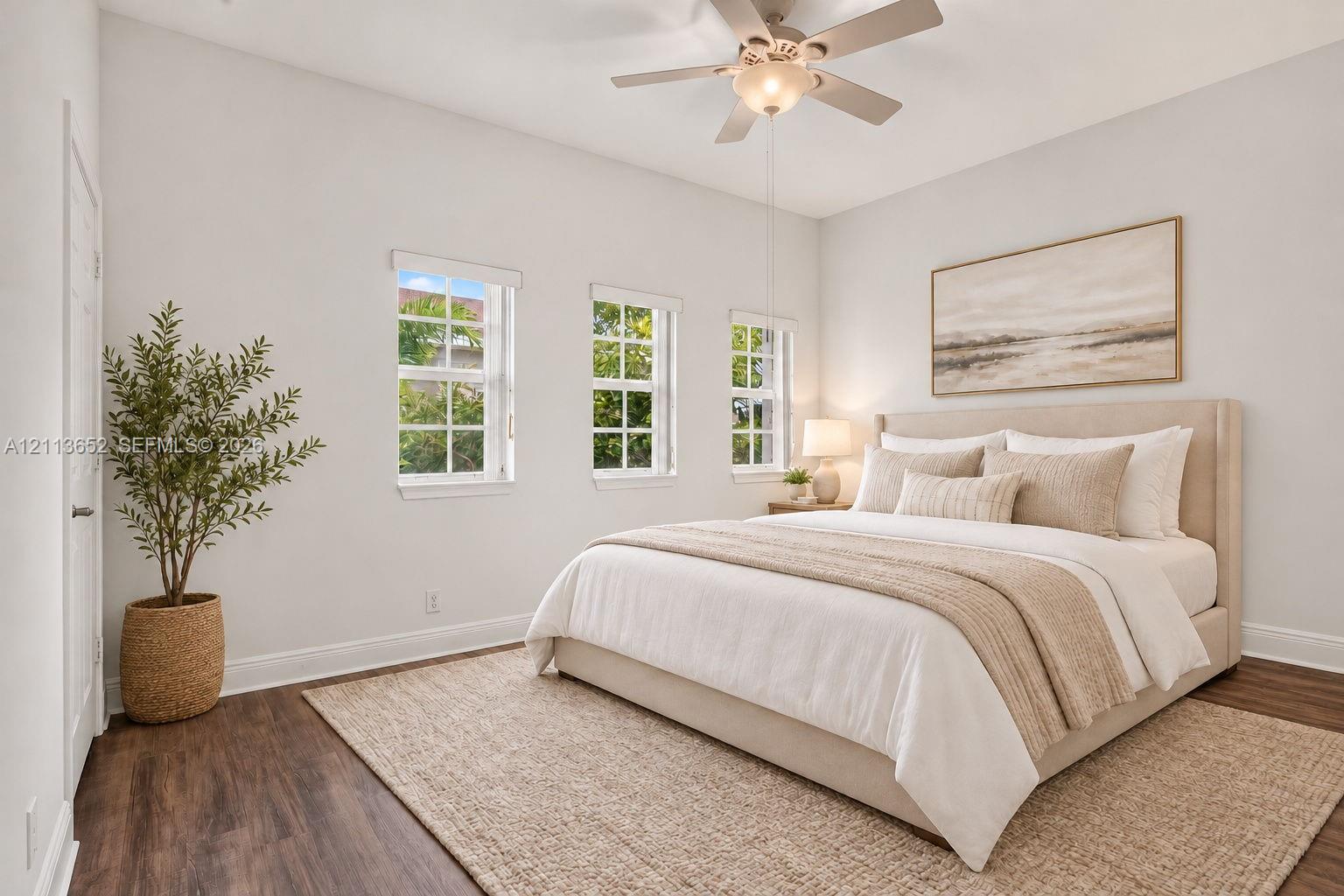 Room with wood-finish flooring, high ceilings, three multi-pane windows, and a central ceiling fan with integrated lighting