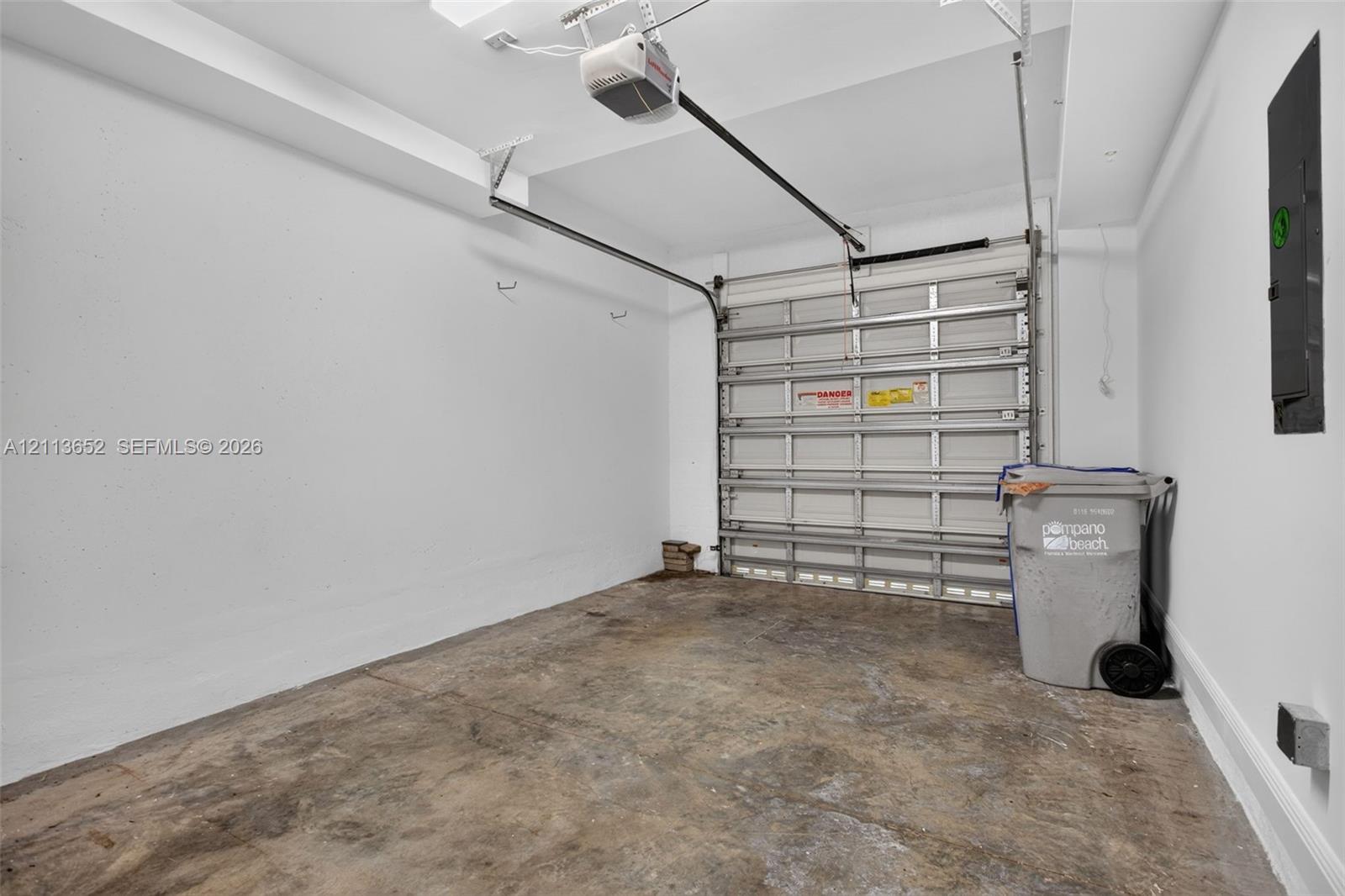 Enclosed garage featuring painted white walls, a metal roll-up door, and an automated door opener