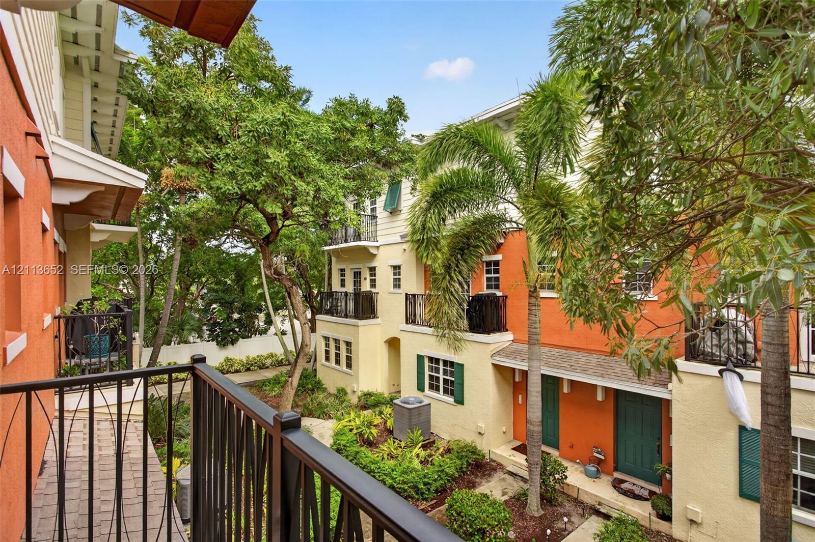 Multi-level exterior featuring stucco siding, wrought-iron balcony railings, arched architectural details, mature landscaping, and paver walkways