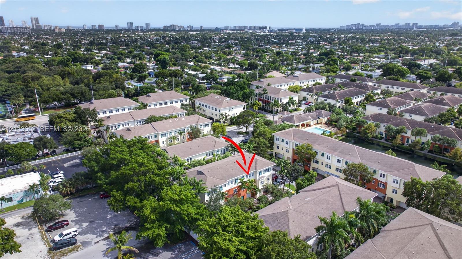 Aerial perspective of a multi-story residential building featuring a pitched roof, light-toned siding, and mature landscaping
