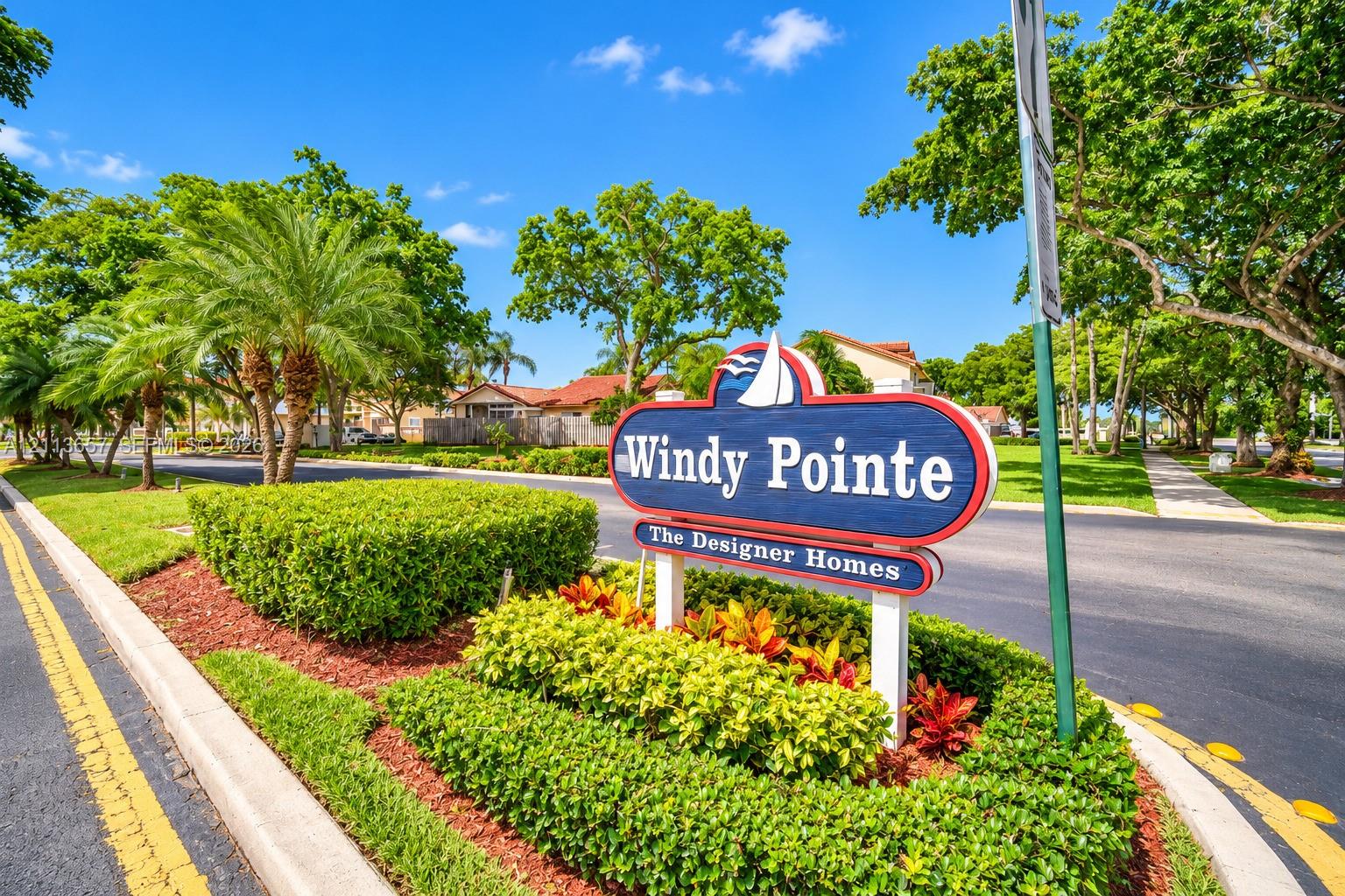 Windy Pointe monument sign featuring professional landscaping, manicured shrubbery, mature trees, and paved roadways