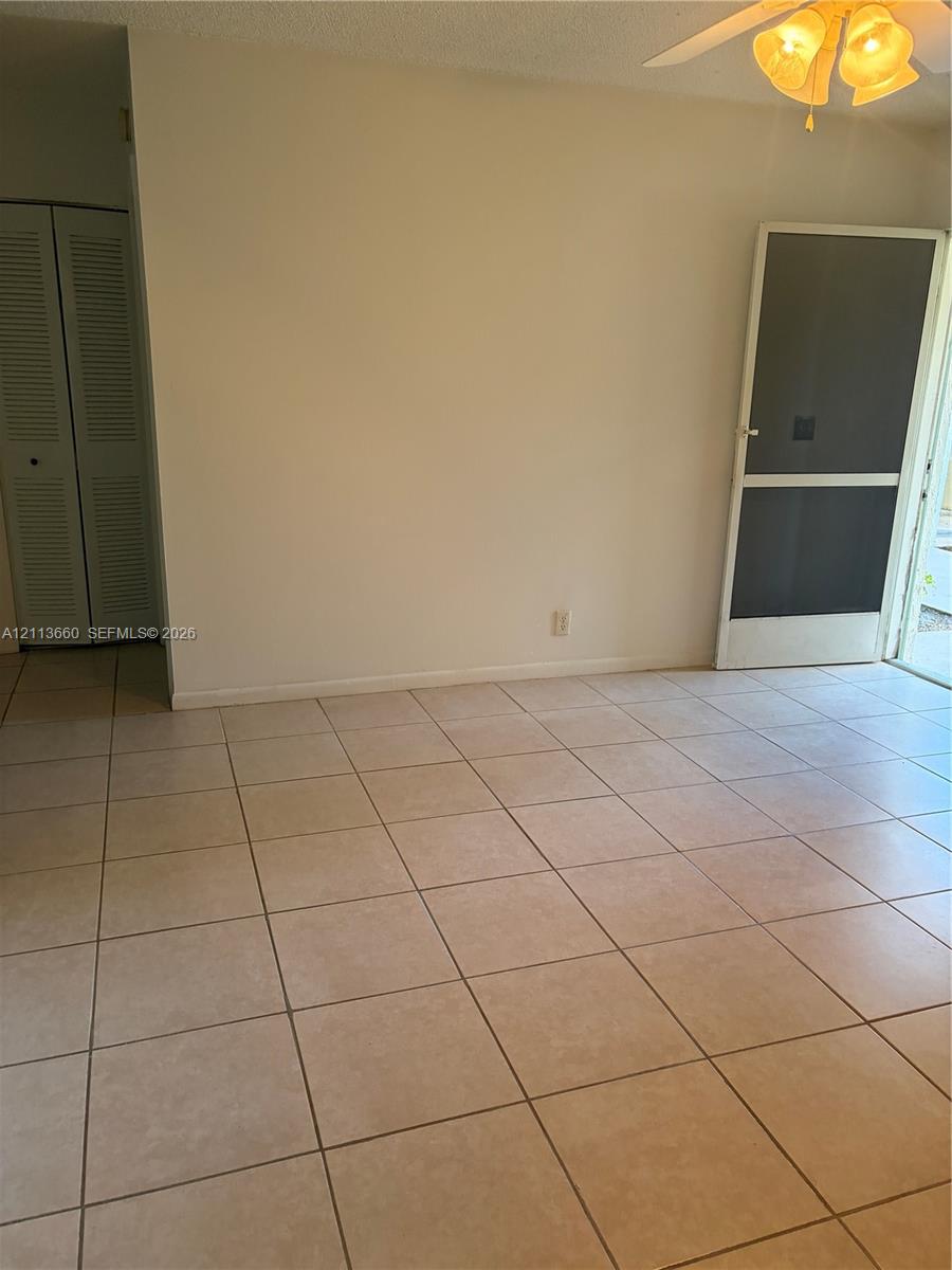 Neutral tile flooring, double-door louvered closet, and ceiling-mounted light fixture