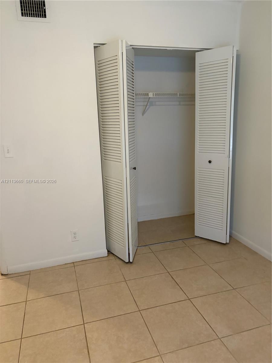 Closet featuring white louvered bifold doors and interior wire shelving, complemented by tile flooring