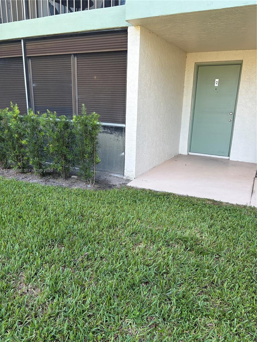 Stucco exterior featuring a covered entryway, solid-core door, and horizontal window shutters