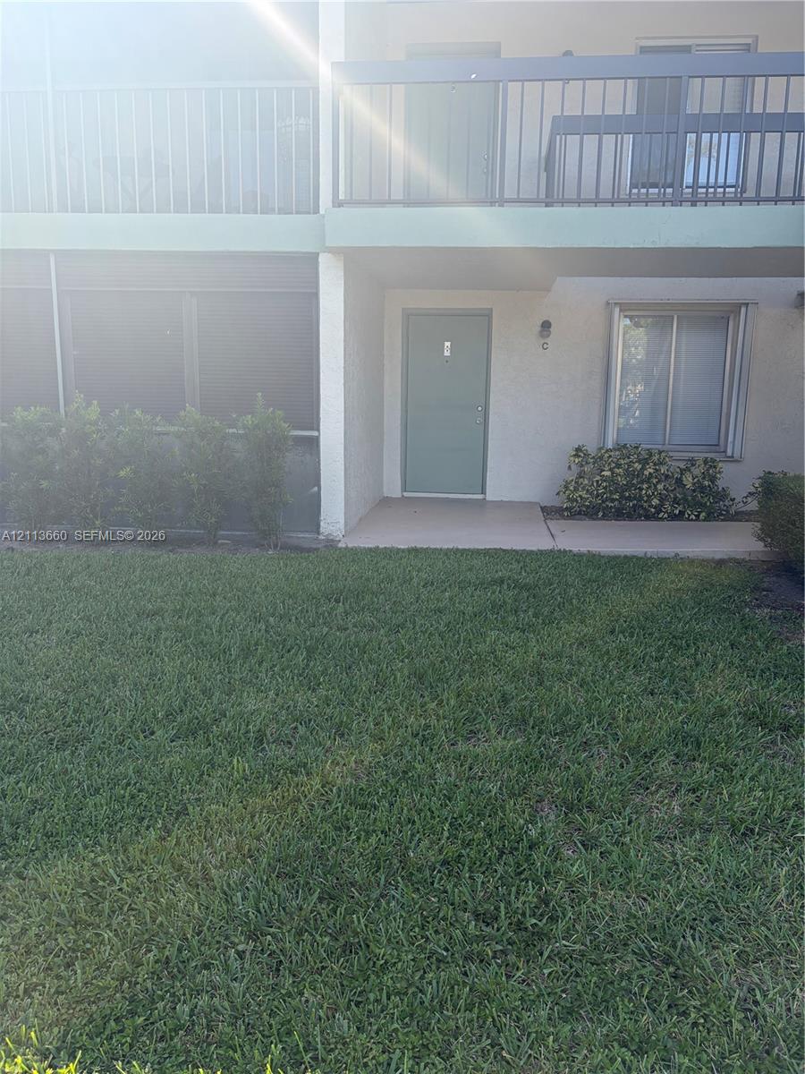 Two-story exterior featuring a private second-level balcony with metal railing, a ground-level covered entryway, and concrete patio surfaces