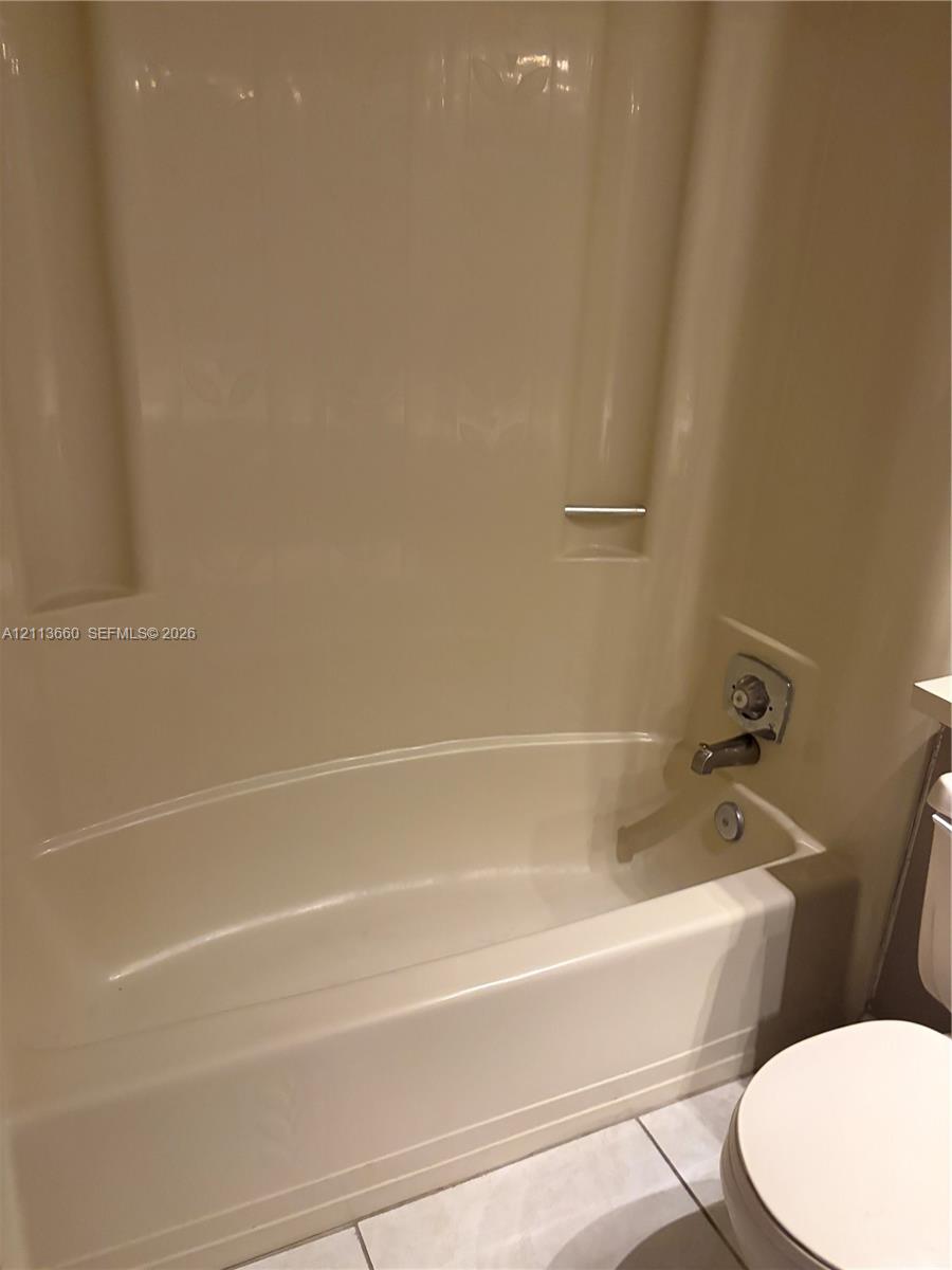 Bathtub and shower combination featuring a seamless surround, integrated soap niche, and metal faucet hardware