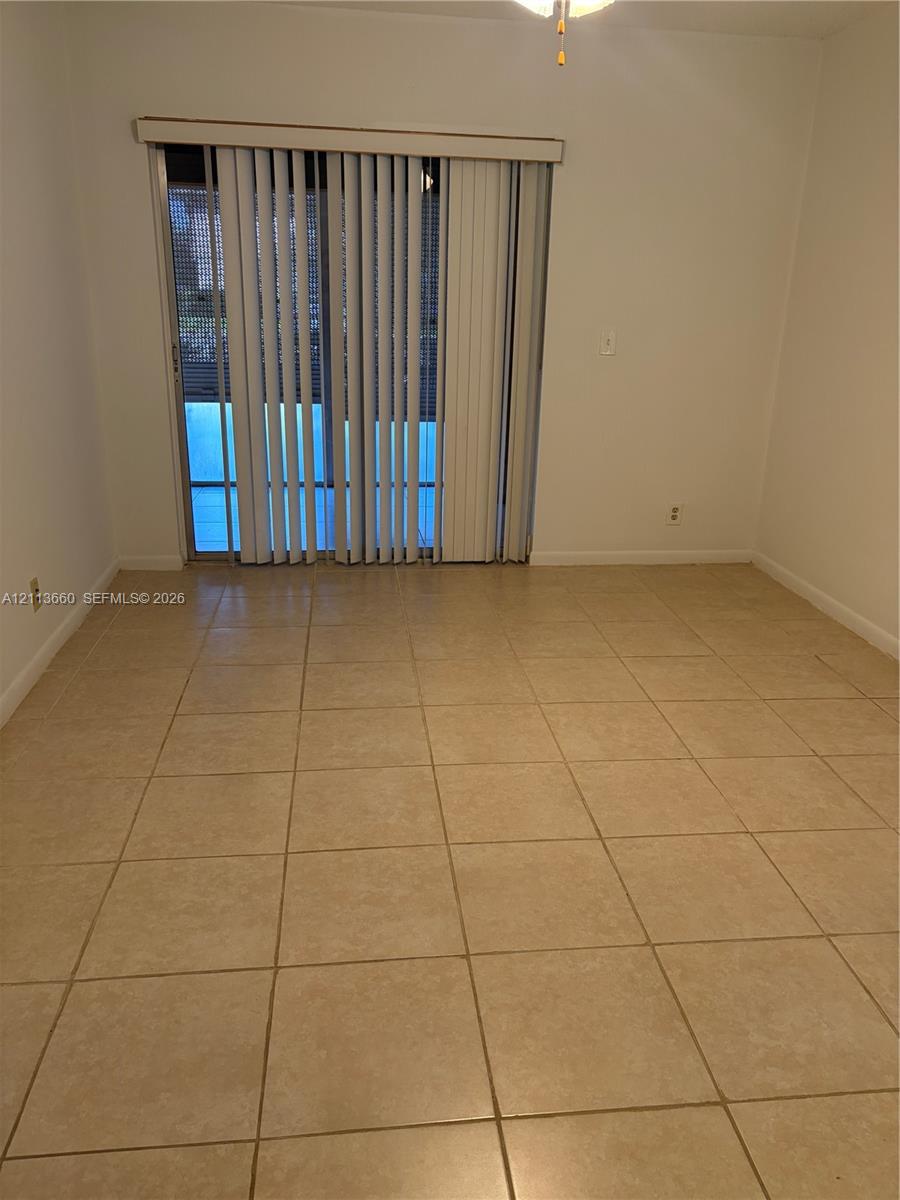 Neutral-toned tile flooring, glass sliding doors with vertical blinds, and a ceiling-mounted light fixture