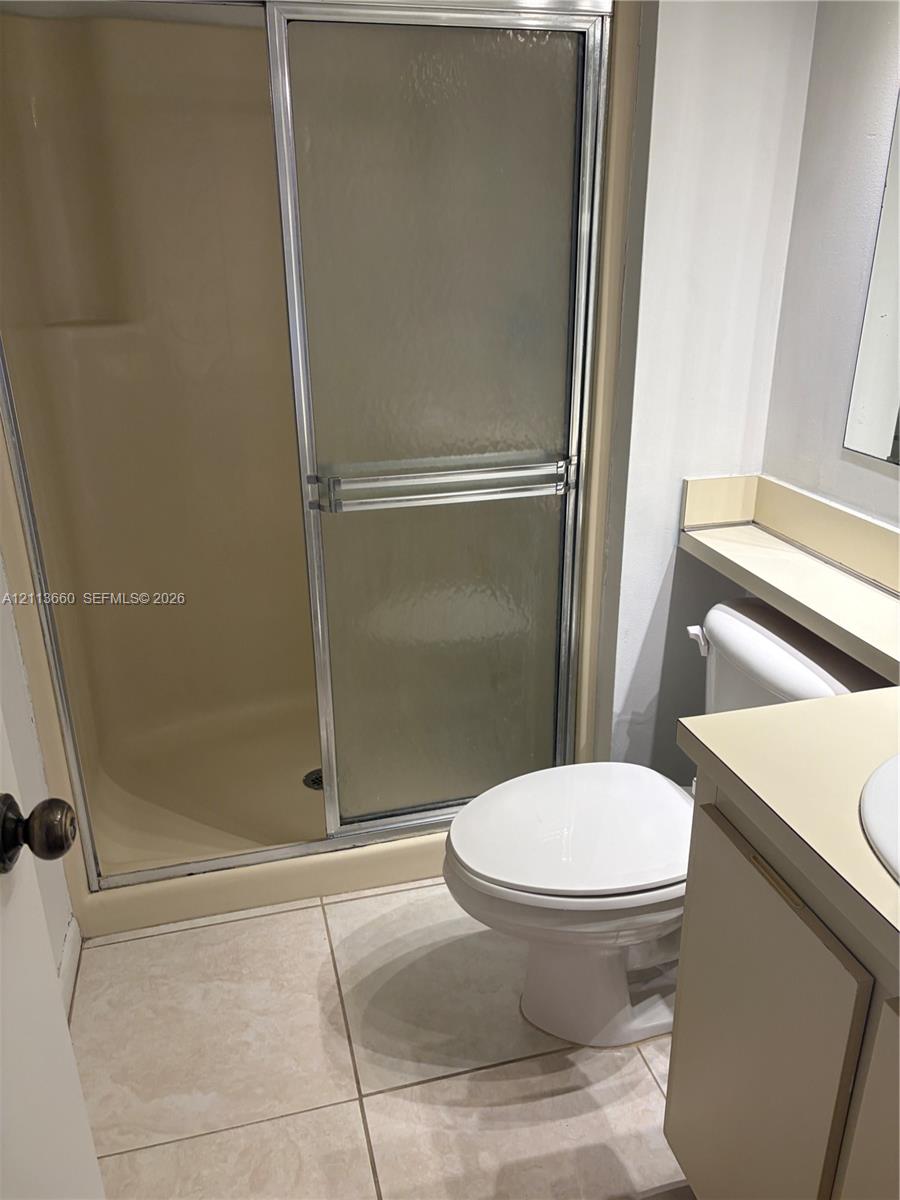 Bathroom featuring a walk-in shower with a sliding glass door, a vanity with a countertop basin, and tile flooring