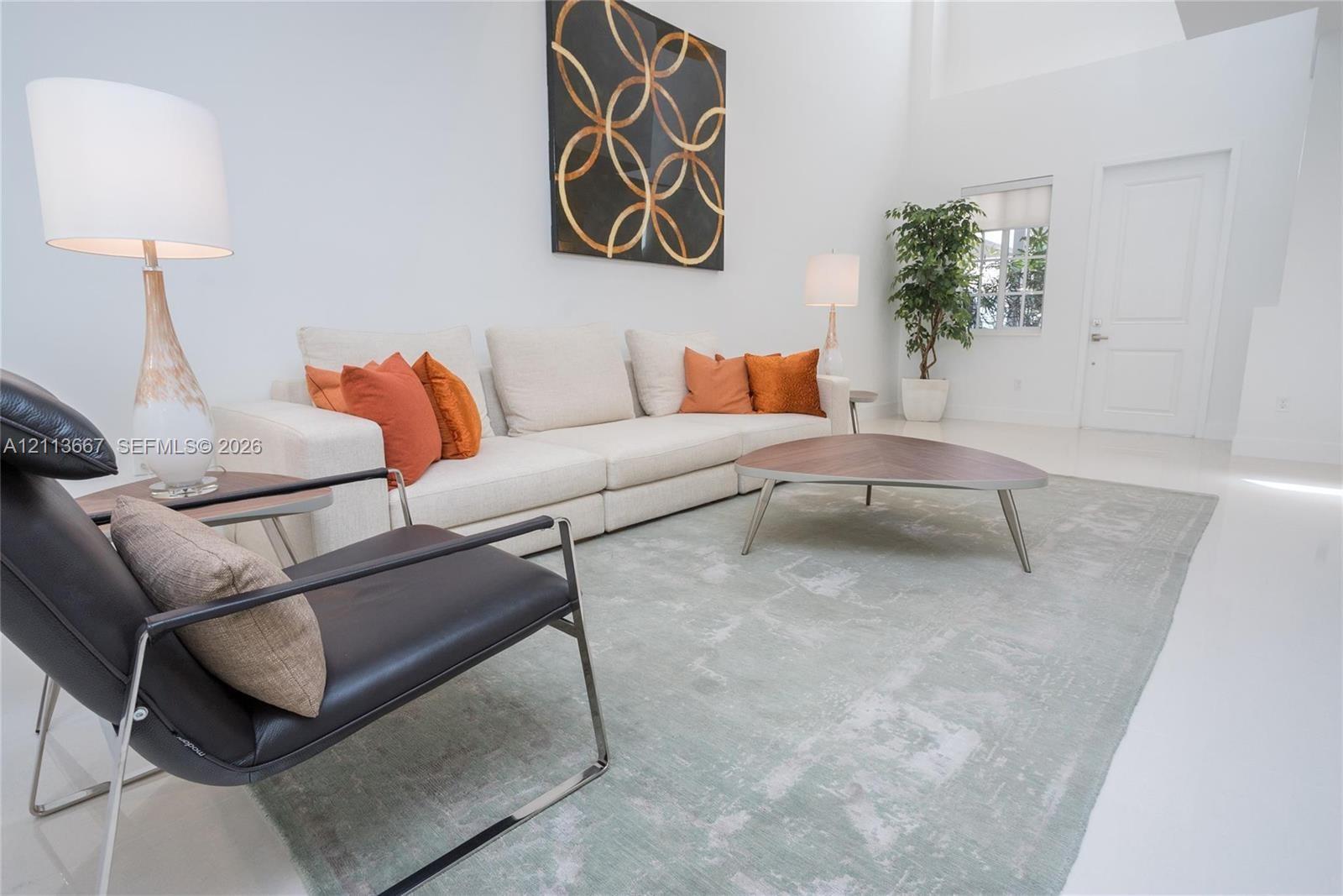 Living area featuring high ceilings, solid surface flooring, and a multi-panel door Living area featuring high ceilings, solid surface flooring, and a multi-panel door