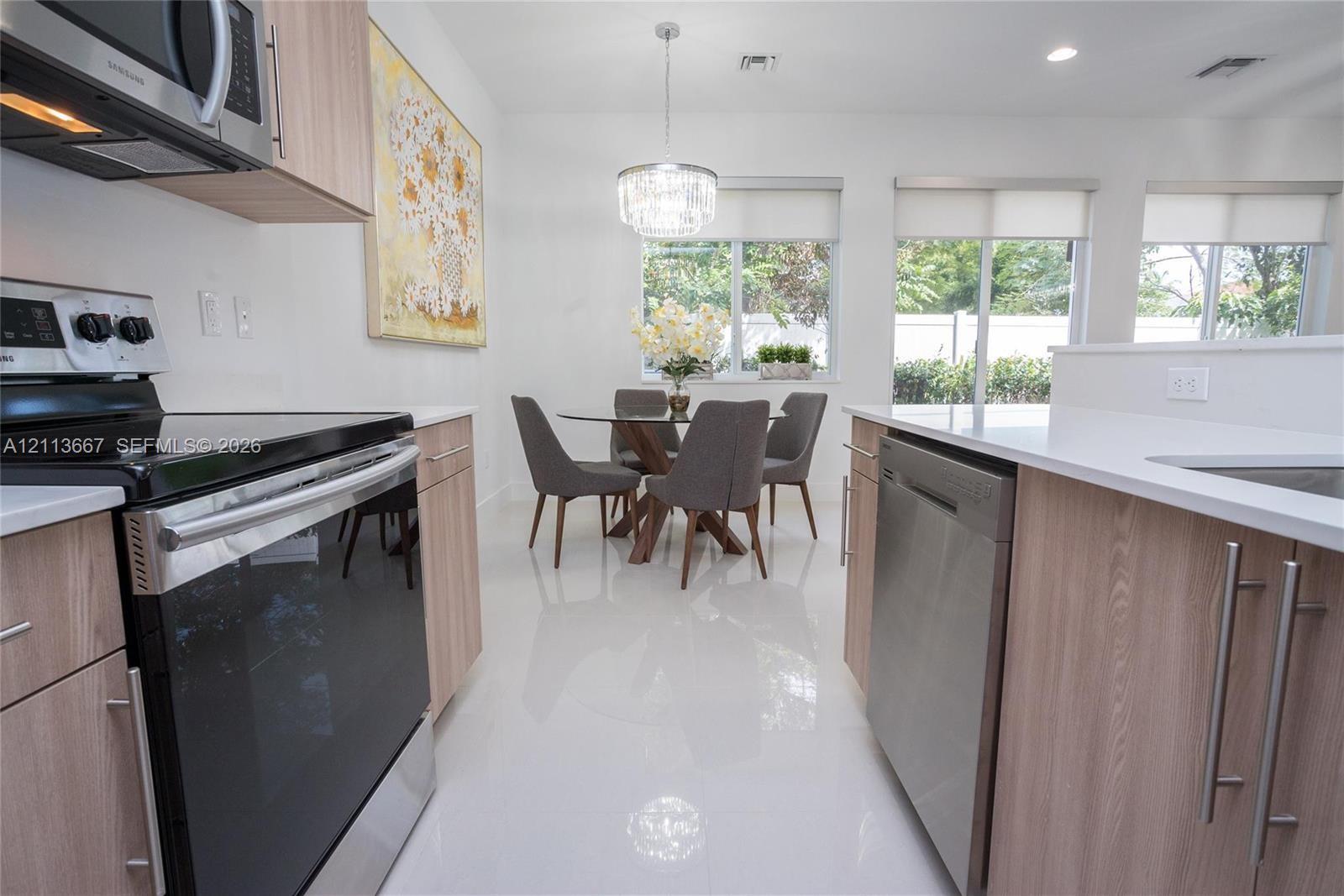 Kitchen featuring light wood-finish cabinetry, white countertops, stainless steel appliances, recessed lighting, and large format tile flooring