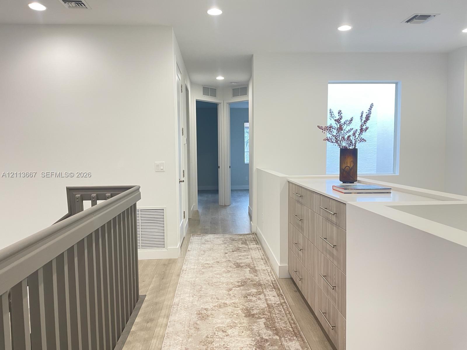 Built-in cabinetry with smooth-finish drawers and a solid surface countertop, wood-finish flooring, and recessed lighting