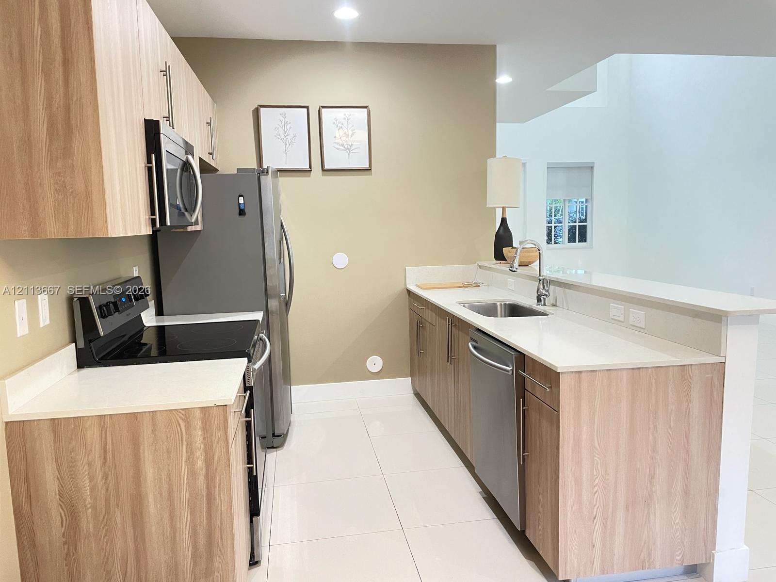 Kitchen featuring light wood-finish cabinetry, white countertops, stainless steel appliances, and tile flooring Kitchen featuring light wood-finish cabinetry, white countertops, stainless steel appliances, and tile flooring
