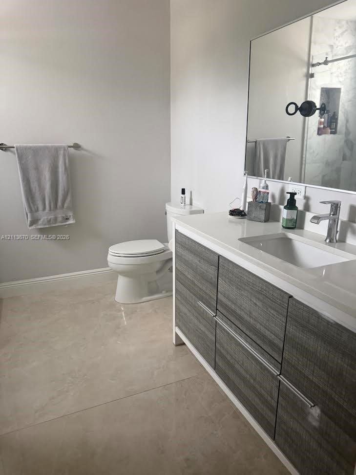 Modern vanity with wood-grain cabinetry, solid surface countertop, rectangular under-mount sink, chrome faucet, and expansive wall-mounted mirror