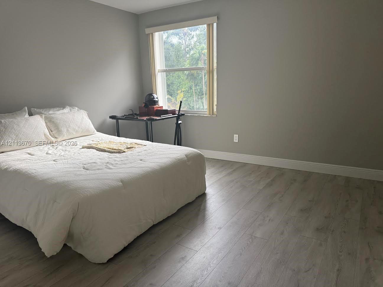 Room featuring wood-finish flooring, neutral wall tones, and a single-hung window with roller shade