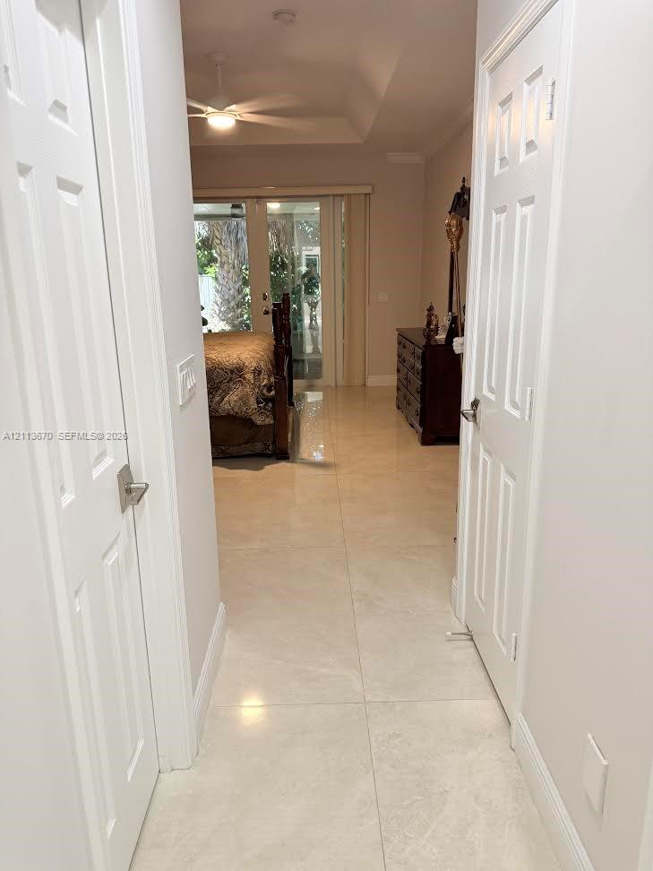 Hallway featuring large-format tile flooring, a tray ceiling, and dual six-panel interior doors