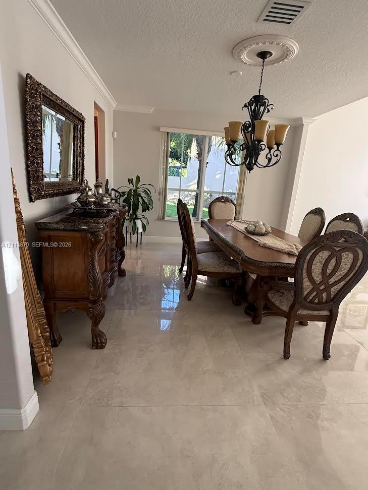Dining area featuring polished large-format tile flooring, crown molding, a decorative ceiling medallion, and a multi-arm metal chandelier Dining area featuring polished large-format tile flooring, crown molding, a decorative ceiling medallion, and a multi-arm metal chandelier