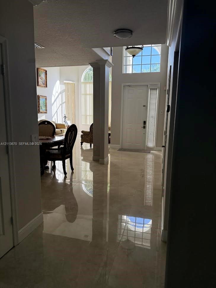 Foyer featuring polished tile flooring, soaring ceilings, decorative columns, arched windows, and a multi-pane glass entry door