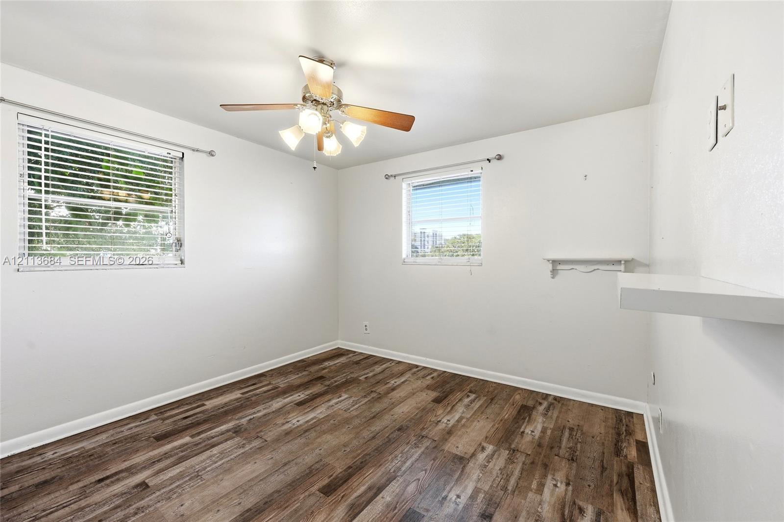 Wood-finish flooring, dual windows with blinds, and ceiling fan with integrated lighting