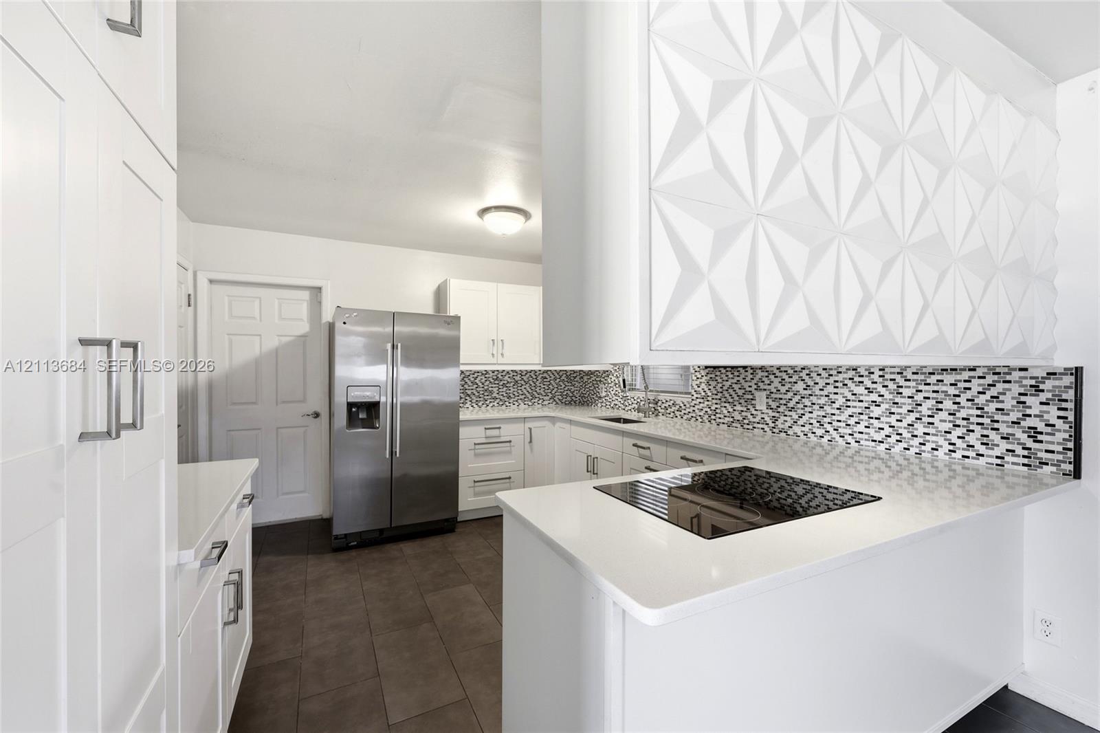 Kitchen featuring white Shaker-style cabinetry, a textured geometric-patterned soffit, stone-surface countertops, a mosaic tile backsplash, and stainless steel appliances