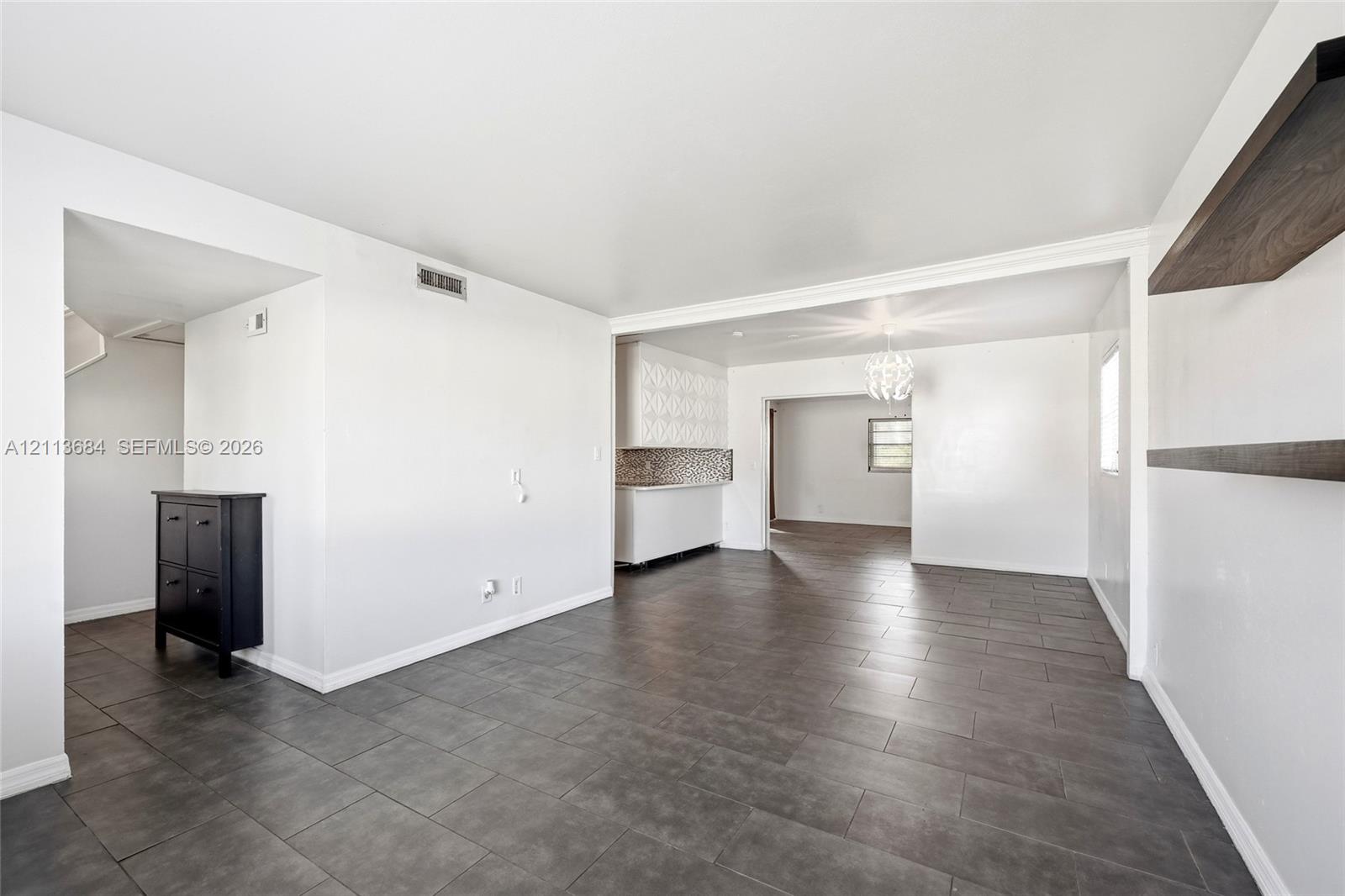 Large-format neutral floor tiling, built-in wall shelving, recessed overhead lighting, and white cabinetry Large-format neutral floor tiling, built-in wall shelving, recessed overhead lighting, and white cabinetry