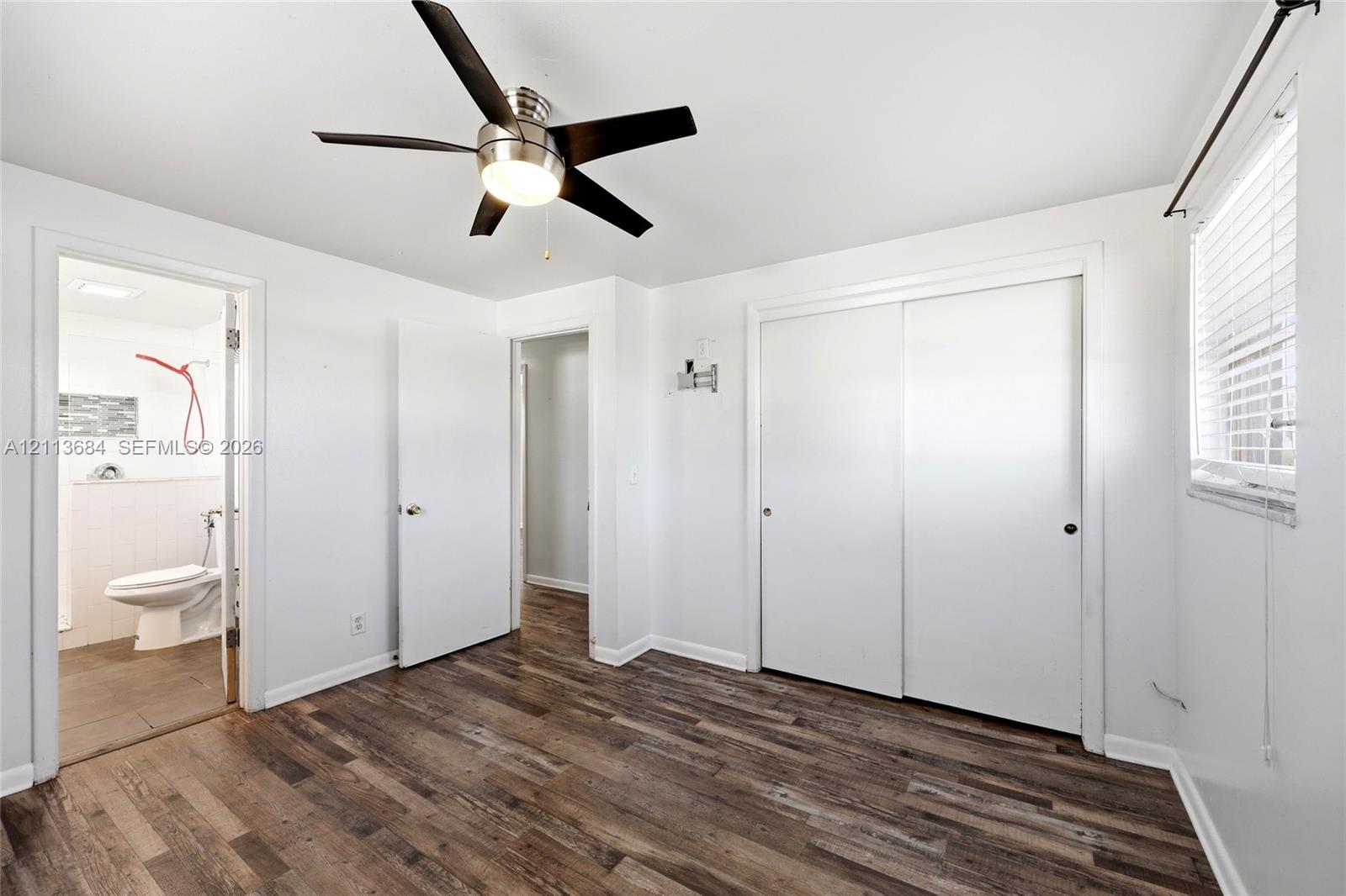Wood-finish flooring, brushed nickel ceiling fan with integrated lighting, and dual-panel sliding closet doors