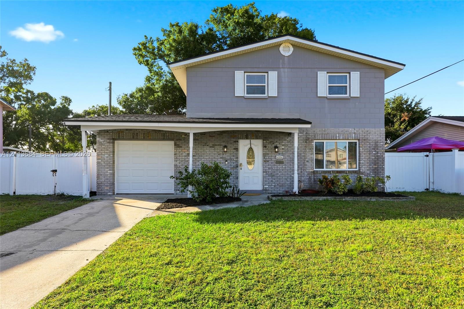 Two-story exterior single-car garage, white vinyl fencing, and shuttered windows