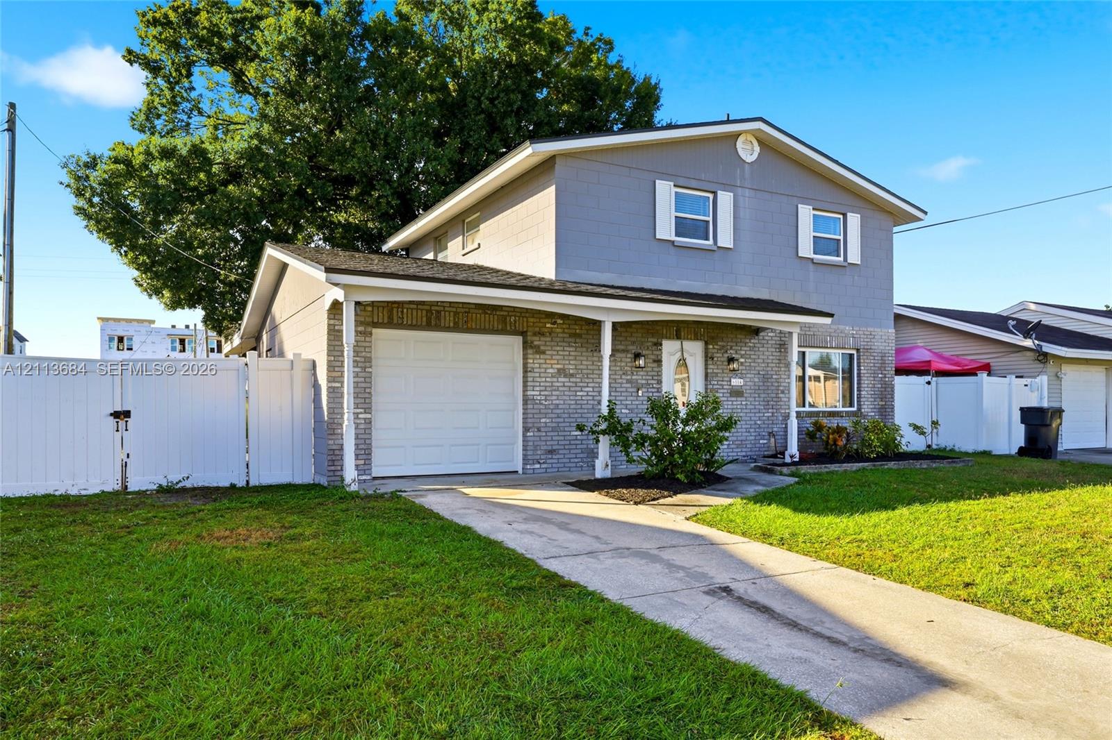 Two-story residence featuring a combination of brick and lap siding exterior, an attached single-car garage, and a covered front porch with a white vinyl fence enclosure Two-story residence featuring a combination of brick and lap siding exterior, an attached single-car garage, and a covered front porch with a white vinyl fence enclosure