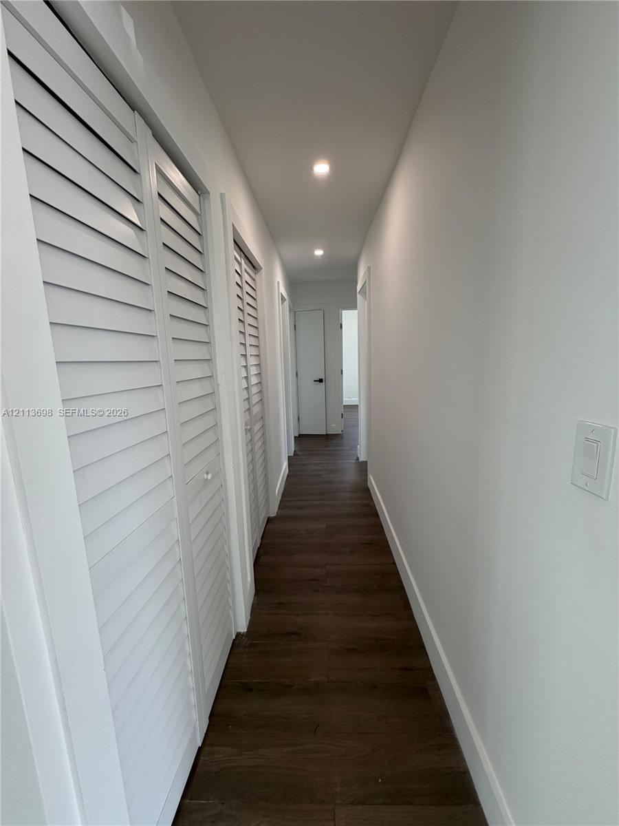 Hallway featuring wood-finish flooring, recessed lighting, and white louvered closet doors