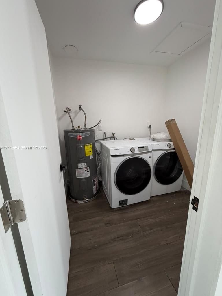 Laundry area featuring wood-finish flooring, ceiling-mounted lighting, and an upright electric water heater