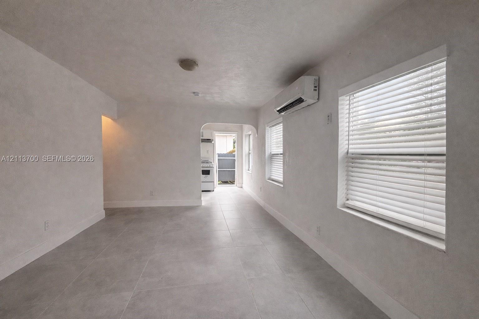 Neutral-toned tile flooring, recessed ceiling lighting, wall-mounted ductless heating and cooling unit, and dual windows with horizontal blinds Neutral-toned tile flooring, recessed ceiling lighting, wall-mounted ductless heating and cooling unit, and dual windows with horizontal blinds