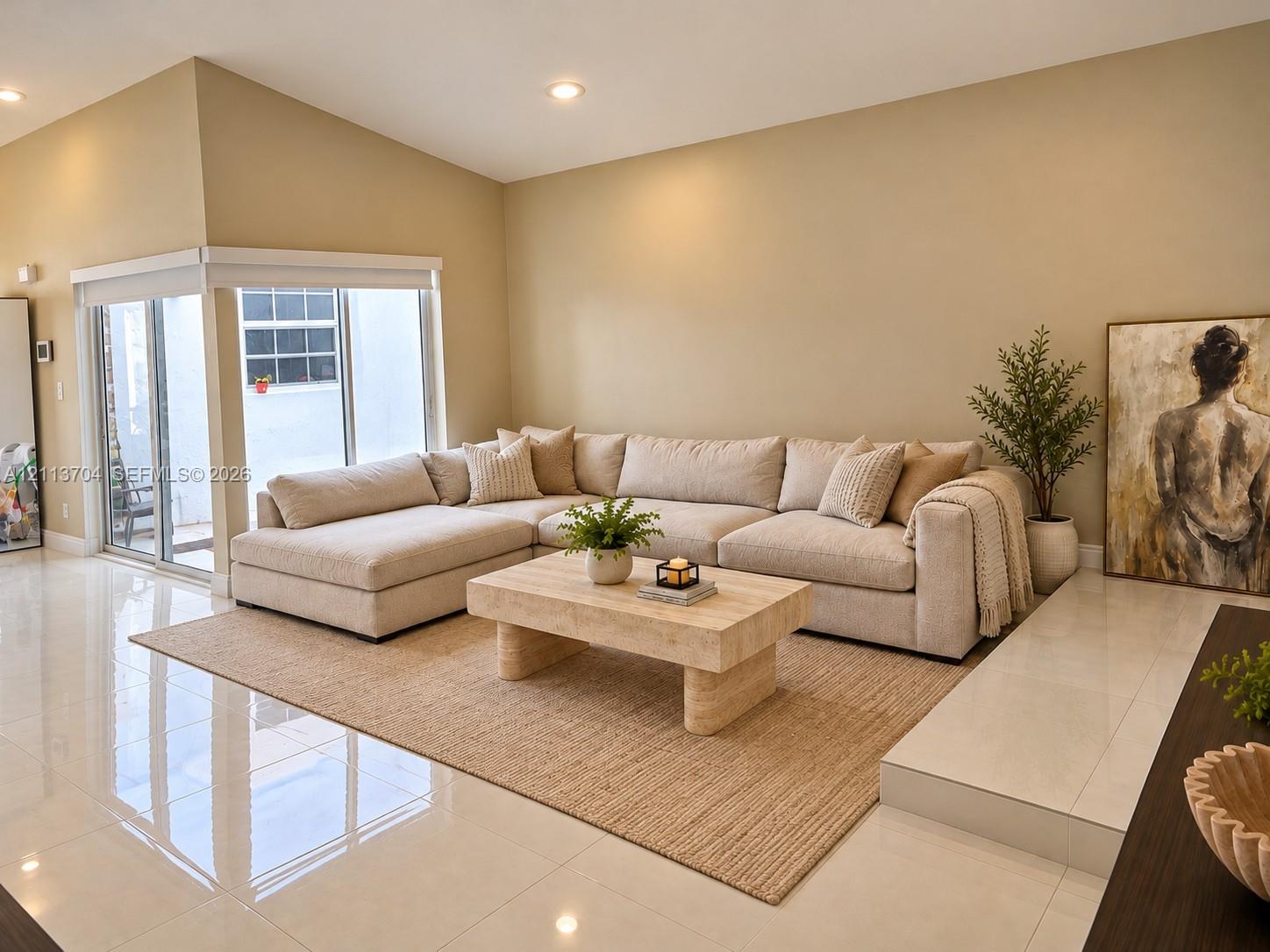 Living area featuring large-format tile flooring, recessed lighting, elevated platform section, and sliding glass doors Living area featuring large-format tile flooring, recessed lighting, elevated platform section, and sliding glass doors