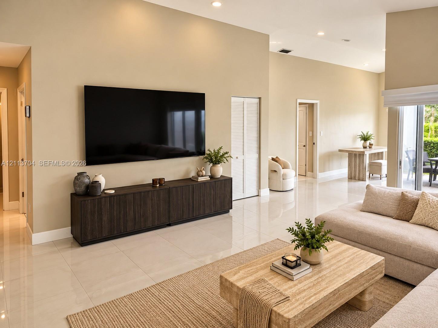 High-ceiling living area featuring large-format tile flooring, recessed lighting, and sliding glass doors High-ceiling living area featuring large-format tile flooring, recessed lighting, and sliding glass doors