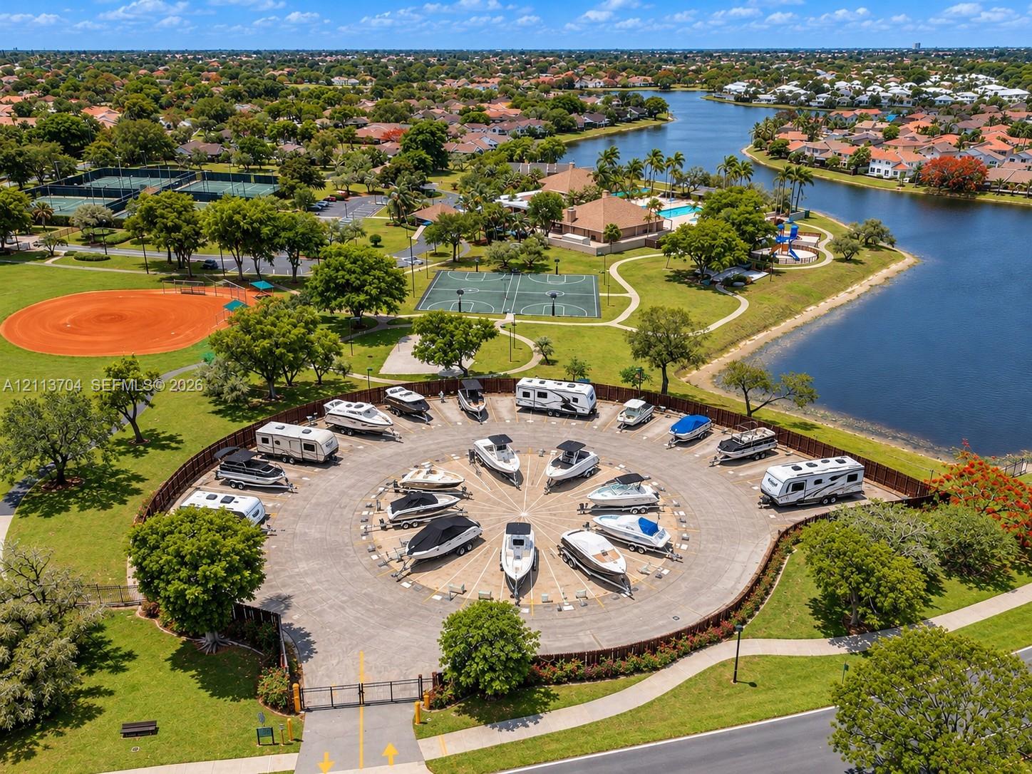 Gated circular storage area featuring paved parking pads for watercraft and recreational vehicles, enclosed by perimeter fencing