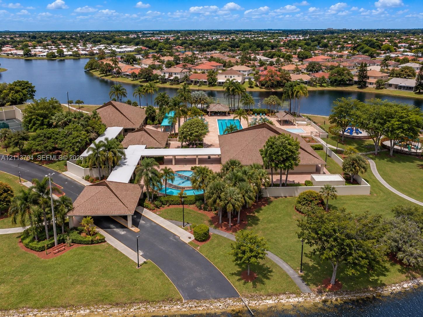 Community center featuring a multi-building complex, outdoor swimming pool, fountain, paved walkways, and lakefront grounds