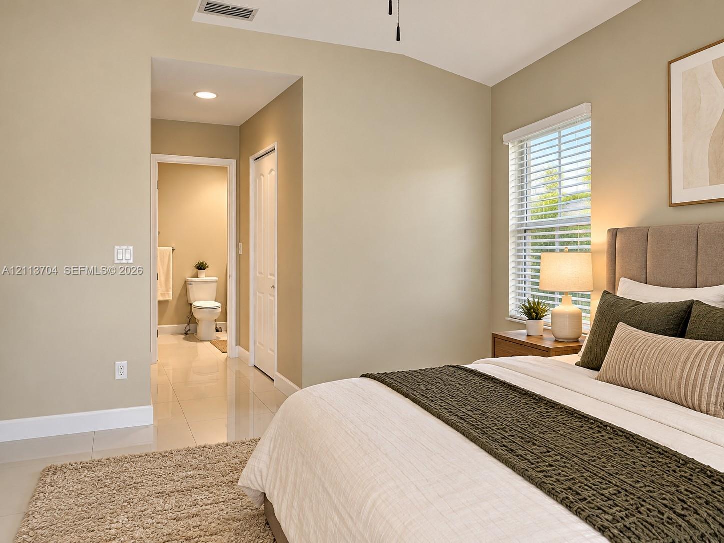 Neutral-toned room featuring high-gloss tile flooring, vaulted ceiling, and window with built-in blinds