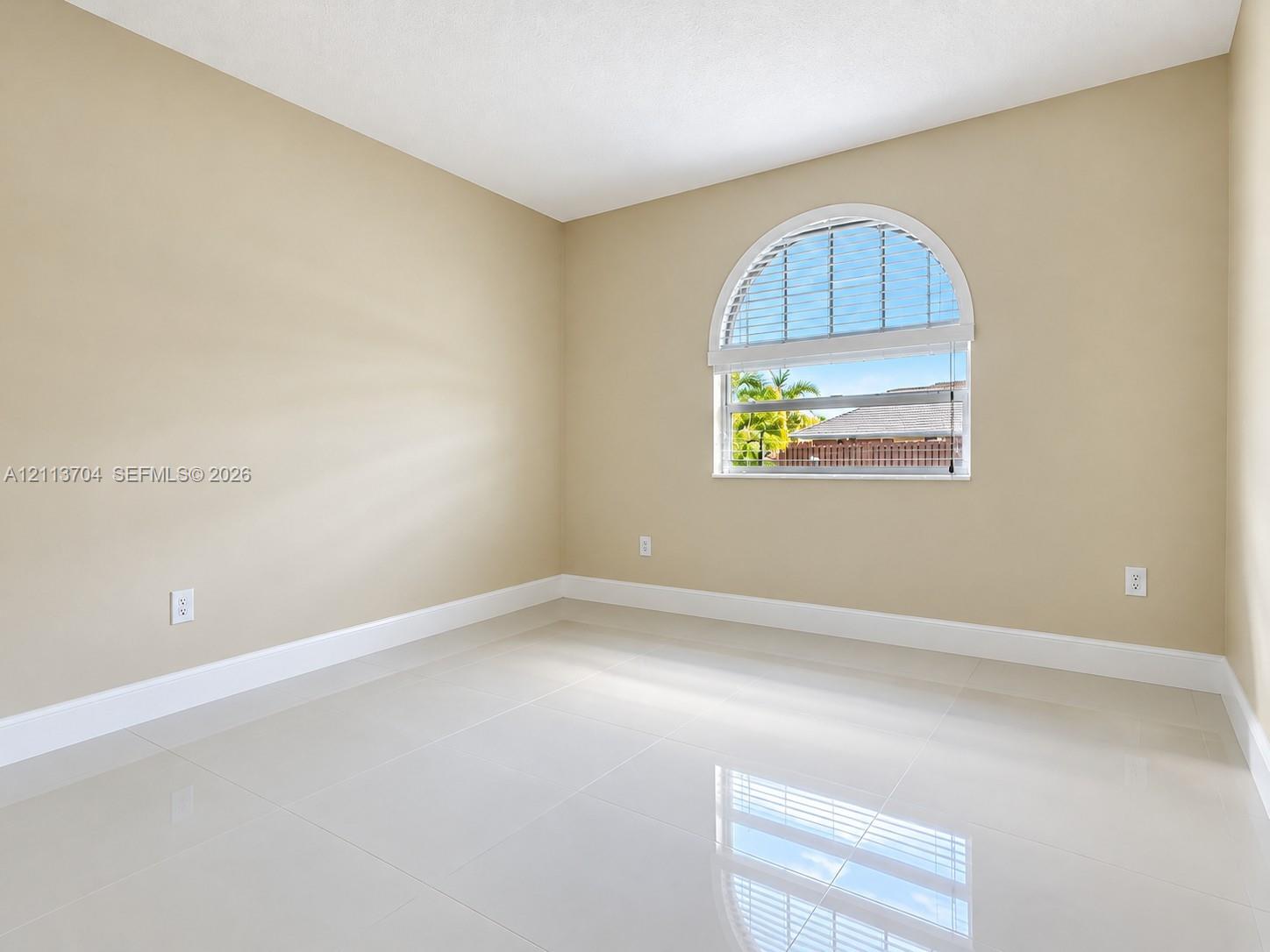 Neutral-toned interior featuring large-format tile flooring and an arched window with an integrated blind Neutral-toned interior featuring large-format tile flooring and an arched window with an integrated blind