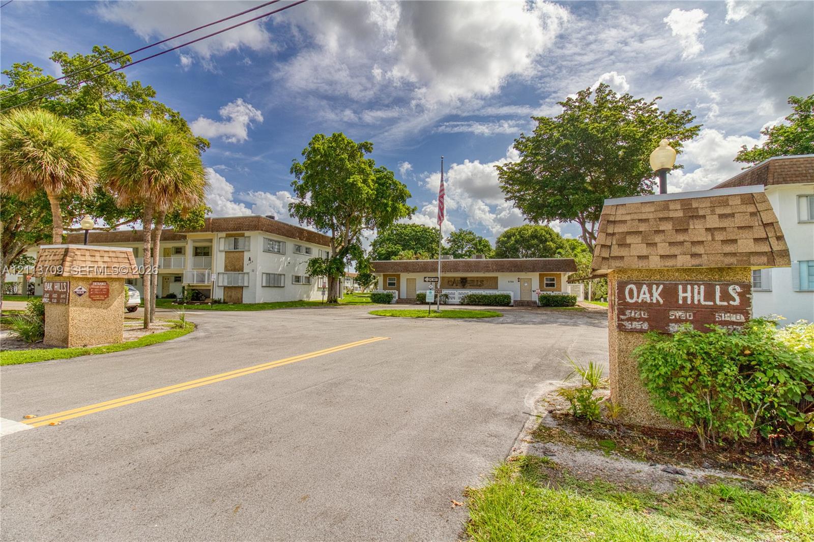 Multi-building property entrance featuring textured masonry signage, mature palm trees, asphalt paving, and established landscaping Multi-building property entrance featuring textured masonry signage, mature palm trees, asphalt paving, and established landscaping
